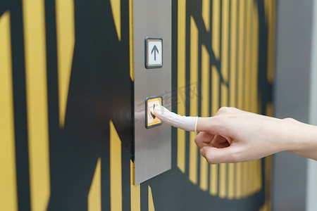 戴橡胶的女人用手指按下电梯的向下按钮