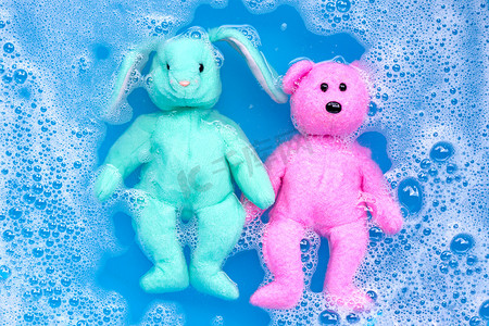 将带玩具泰迪熊的兔子娃娃浸泡在洗衣粉水中