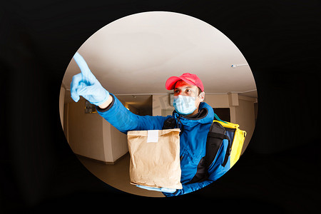 与或非摄影照片_送货员将食品袋送到门把手处，以实现非接触式或免接触式，与前屋的送货员保持社交距离，以防止感染风险。