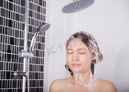女人用洗发水在花洒淋浴中洗头和头发