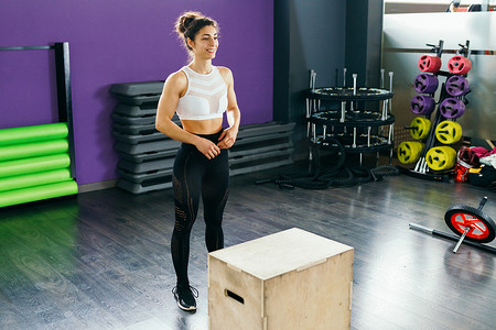 日常装备摄影照片_健身妇女跳上箱子作为日常锻炼的一部分。