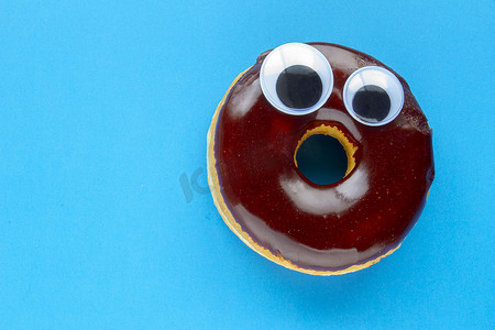 蓝色背景上的 Tim Hortons 巧克力甜甜圈，上面有黑色的眼球