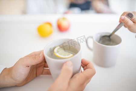 手拿着一杯柠檬茶放在白桌上