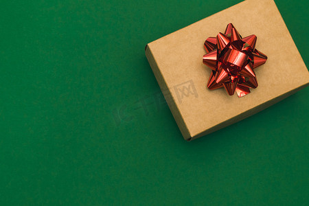 蝴蝶结边框摄影照片_圣诞边框与工艺礼品盒和绿色背景上的红色蝴蝶结。