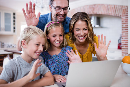 父母和孩子视频摄影照片_父母和孩子在使用笔记本电脑进行视频聊天时挥手