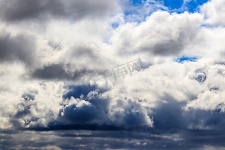 蓝色天空的云摄影照片_明亮的蓝色天空，在白天的阳光照射下，有戏剧性的积云。