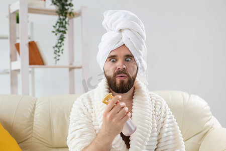 皮肤喷雾摄影照片_留着胡子的男性头上戴着浴巾，在脸上进行喷雾水处理。