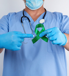 蓝色制服和乳汁手套的医生拿着一条绿色丝带