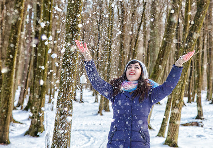 在树林里玩雪的年轻漂亮女人的画像