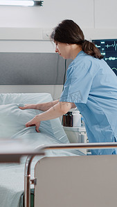女护士在医院病房整理床位以进行医疗保健