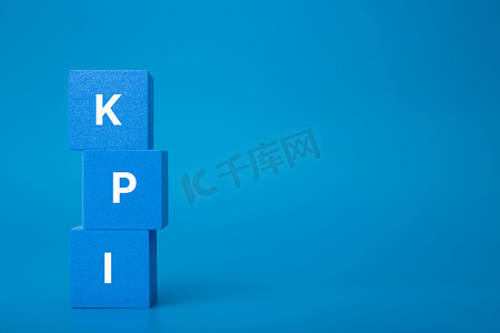 深蓝色背景下蓝色玩具立方体堆上的 KPI 字母，带有复制空间