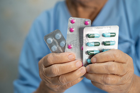 亚洲老年或老年老妇患者拿着泡罩包装的抗生素胶囊药丸，用于治疗医院感染患者；
