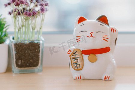 金色的文字摄影照片_Maneki neko 招财猫手头上的文字，意思是桌上有钱，s