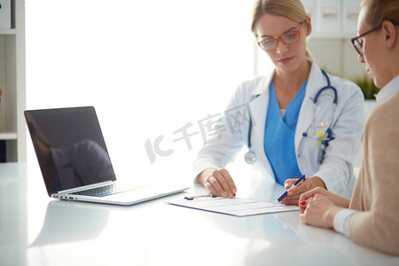医生和病人夫妇坐在桌子上正在讨论一些事情。