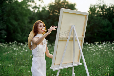 学生画画摄影照片_穿白裙的女人在户外画了一幅爱好创意的画