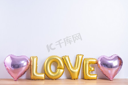 情人节，母亲节设计理念 — 美丽的气球，在浅色木地板和白墙背景上，有爱字形状，特写。