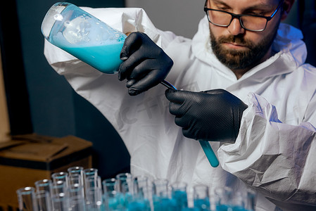 一位身穿防护服、装有蓝色疫苗液的男科学家