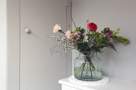 玻璃花瓶中美丽的春花，靠近时尚家居的灰色墙壁，现代室内装饰与复制空间