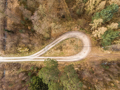 大视野背景摄影照片_从有大云杉、松树和冷杉的森林山脊的转弯环垂直拍摄的航拍照片，抽象的空中视野