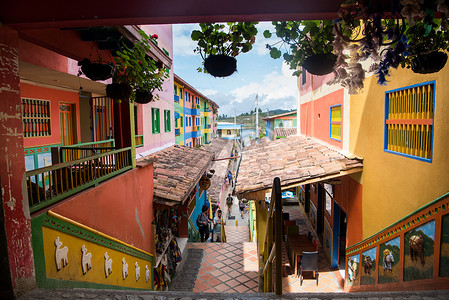 哥伦比亚瓜塔佩市中心的建筑物上有彩色图案，悬挂着盆花。