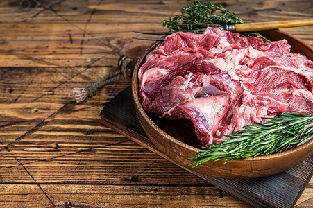 蒸羊腿摄影照片_无骨生羊肉羊肩肉在木盘与香草。