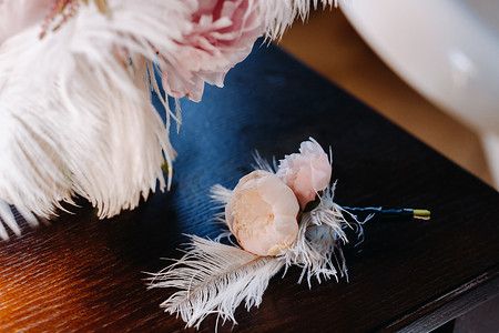 婚礼胸花摄影照片_新娘的婚礼玫瑰花束装饰着白色羽毛和胸花