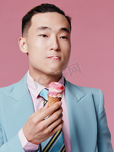 韩国经典摄影照片_身穿蓝色经典西装、冰淇淋肖像粉色背景模型的男子特写裁剪视图