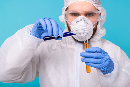 细胞防护摄影照片_Covid-19、疫苗开发、流行病、爆发和冠状病毒概念 — 男科学家穿着个人防护装备，拿着试管，进行化学实验。