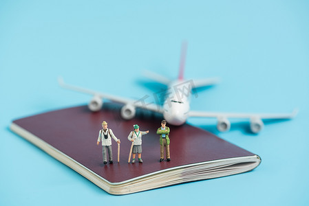 签证飞机摄影照片_护照簿上的微型旅行者和飞机模型