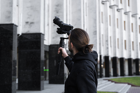 年轻的专业摄像师在 3 轴万向稳定器上手持专业相机。