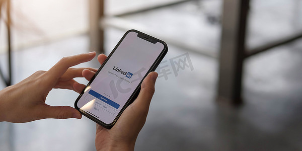 泰国清迈，2020 年 12 月 12 日：一位女士拿着苹果 iPhone X，屏幕上显示 LinkedIn 应用程序。LinkedIn 是一款智能手机照片共享应用程序。