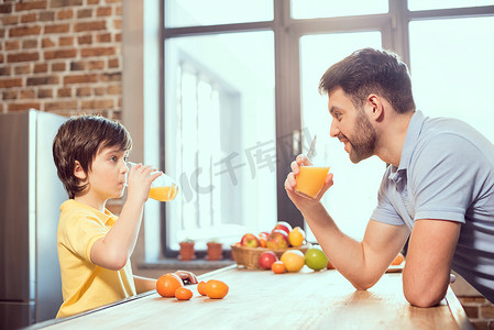 快乐的父子一起喝新鲜果汁的侧视图