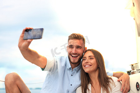 海上旅游摄影照片_幸福的情侣在帆船上求婚后自拍，在海上的游艇上放松。