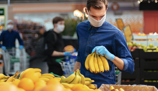 家电卖场开业摄影照片_戴着防护手套的男子在超市挑选香蕉。
