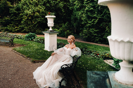 新娘在花园里，新娘坐在长凳上，新娘聚会，早晨新娘，白色礼服，戴上耳环。