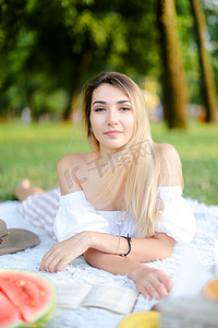 漂亮的花纹摄影照片_年轻漂亮的女孩躺在公园的格子上看书。