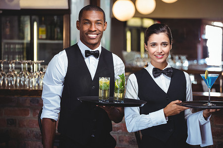 酒店女服务员摄影照片_服务员和女服务员拿着一个盛有鸡尾酒的托盘