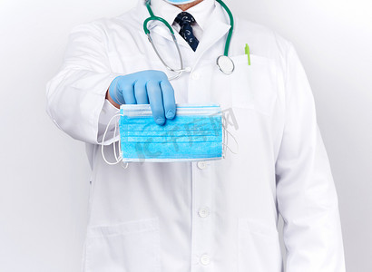 一件白色外套的医生，蓝色乳汁无菌手套拿着纺织品
