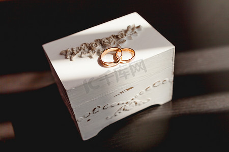 一对金色结婚戒指，白色破旧装饰盒上镶有钻石。