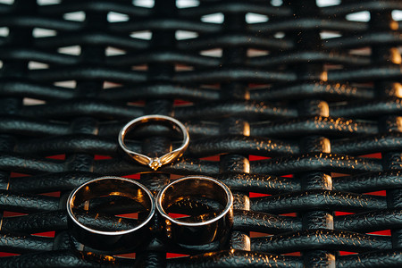 方格网格摄影照片_方格网格上有两枚结婚戒指和一枚订婚戒指。