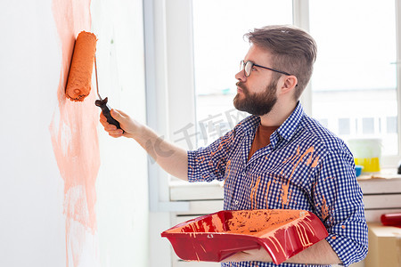 男性用油漆滚筒粉刷墙壁。