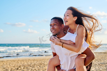 年轻美丽的情侣在大海背景下玩得开心
