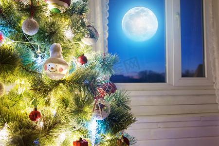 装饰月亮摄影照片_圣诞家庭房间，窗户上有树和月亮照明。