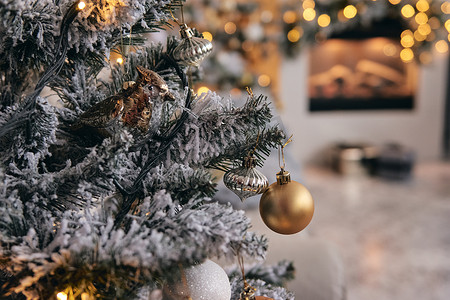舒适的房间装饰着，银色雪中的圣诞树，下面有金色的泡泡玩具、灯光和礼物。