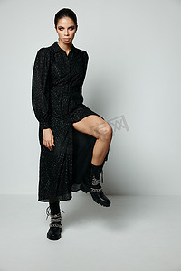 漂亮的黑发亮妆黑色连衣裙腿弯曲膝盖时尚