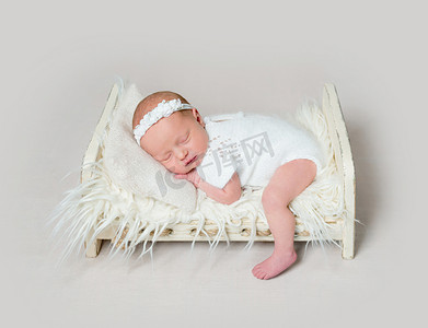 动态问好带字摄影照片_可爱的新生婴儿睡在婴儿床上，腿放在地板上