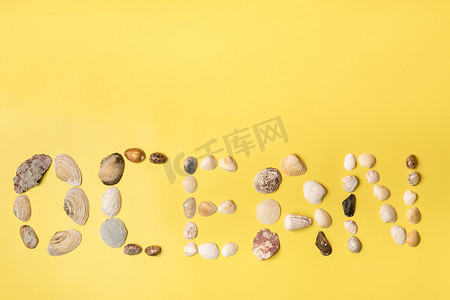 黄色背景上贝壳制成的“海洋”一词的铭文。旅行概念
