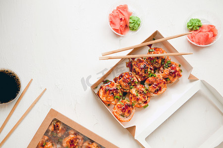 白色背景纸包装中的烘焙寿司 — 平铺，配有生姜和芥末 — 盒装明亮美味的寿司卷