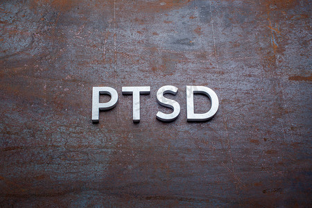 平铺摄影照片_PTSD这个词在平生锈的钢板背景上用银色金属字母以直透视的方式铺设