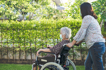 老人健康摄影照片_医生帮助和护理亚洲老年或老年老妇女病人坐在护理医院病房公园的轮椅上，健康强大的医疗理念。